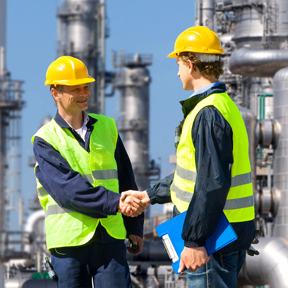 Two petrochemical contractors closing a deal in front of an oil refinary